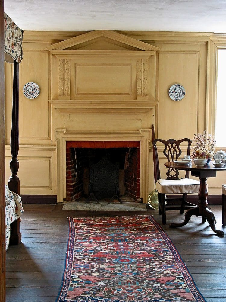 A fireplace in the center of a room with a table and chairs.