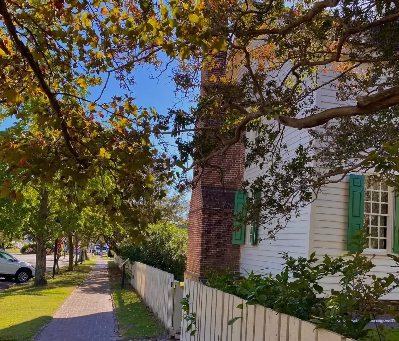 A white fence with green shutters on the side of it.