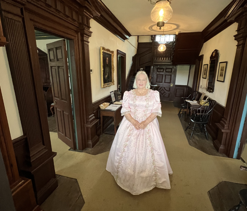 A woman in white dress standing inside of a room.