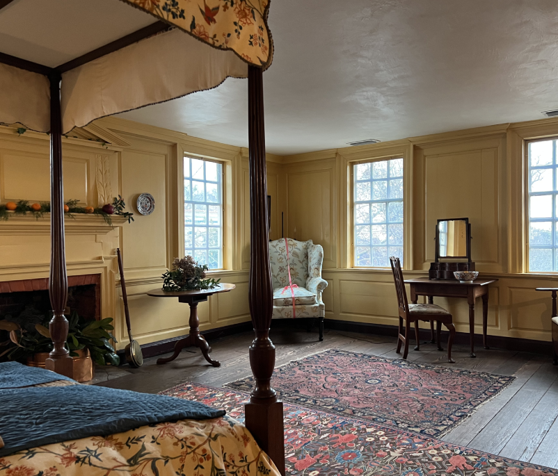 A bedroom with four poster bed and large rug.