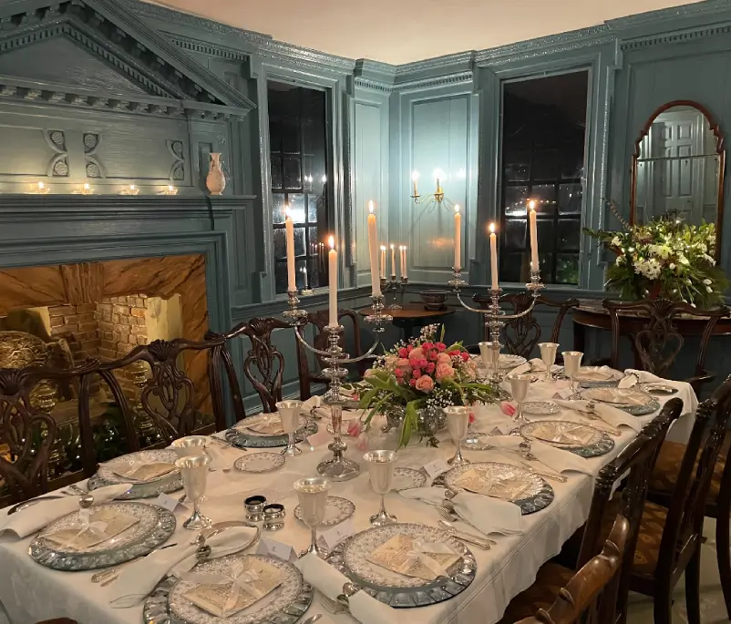 A dining room table with plates and candles on it.