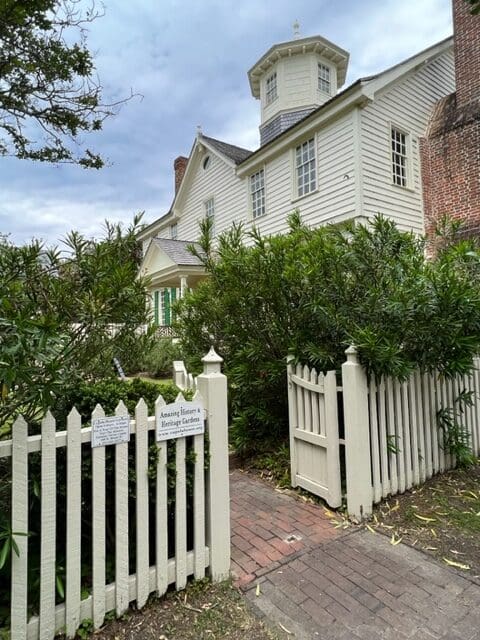 A white picket fence and gate in front of a house.