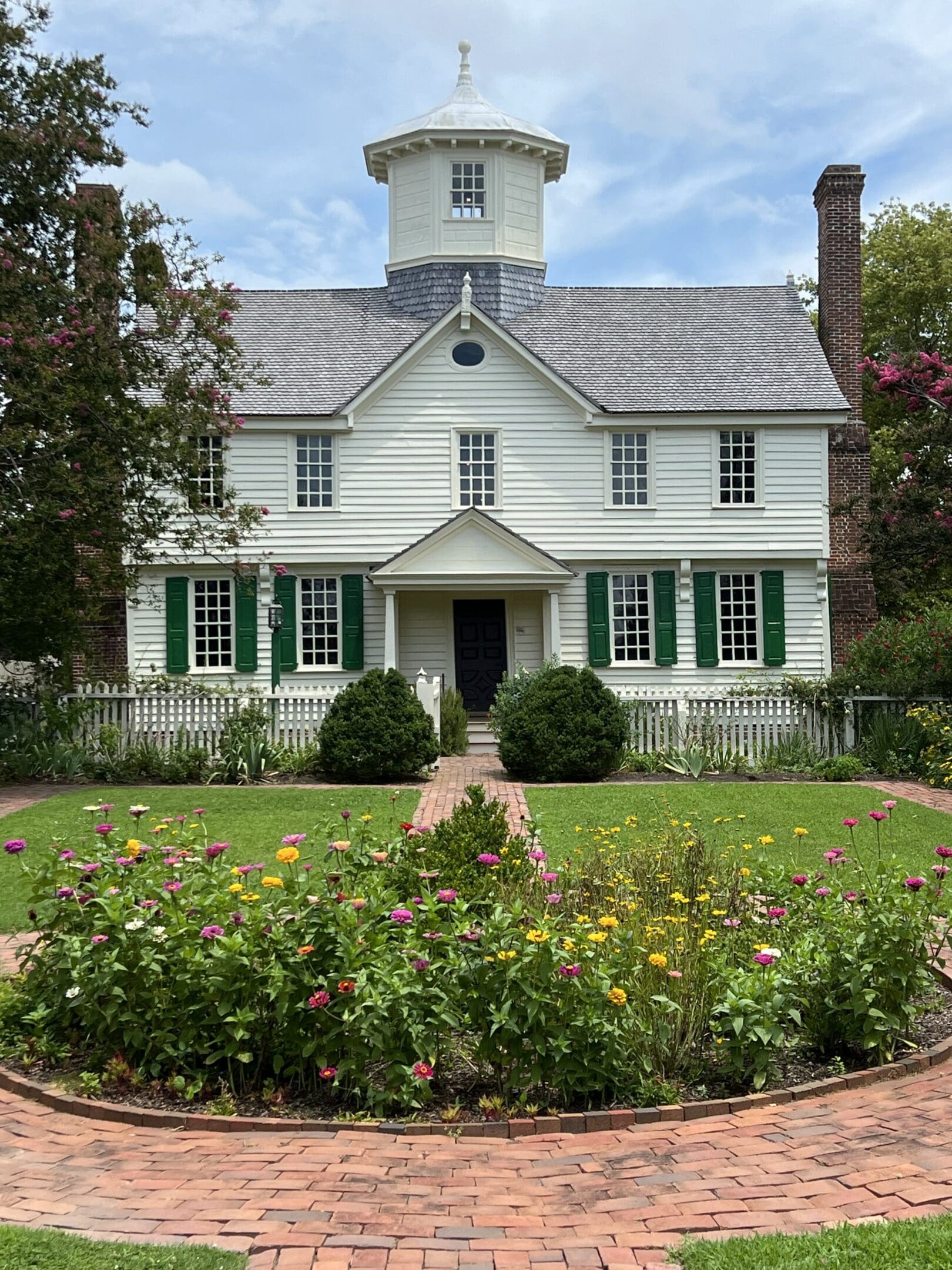 A white house with green shutters and a garden.