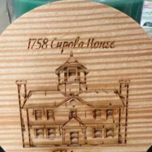 Wooden plaque with engraved historic building design.